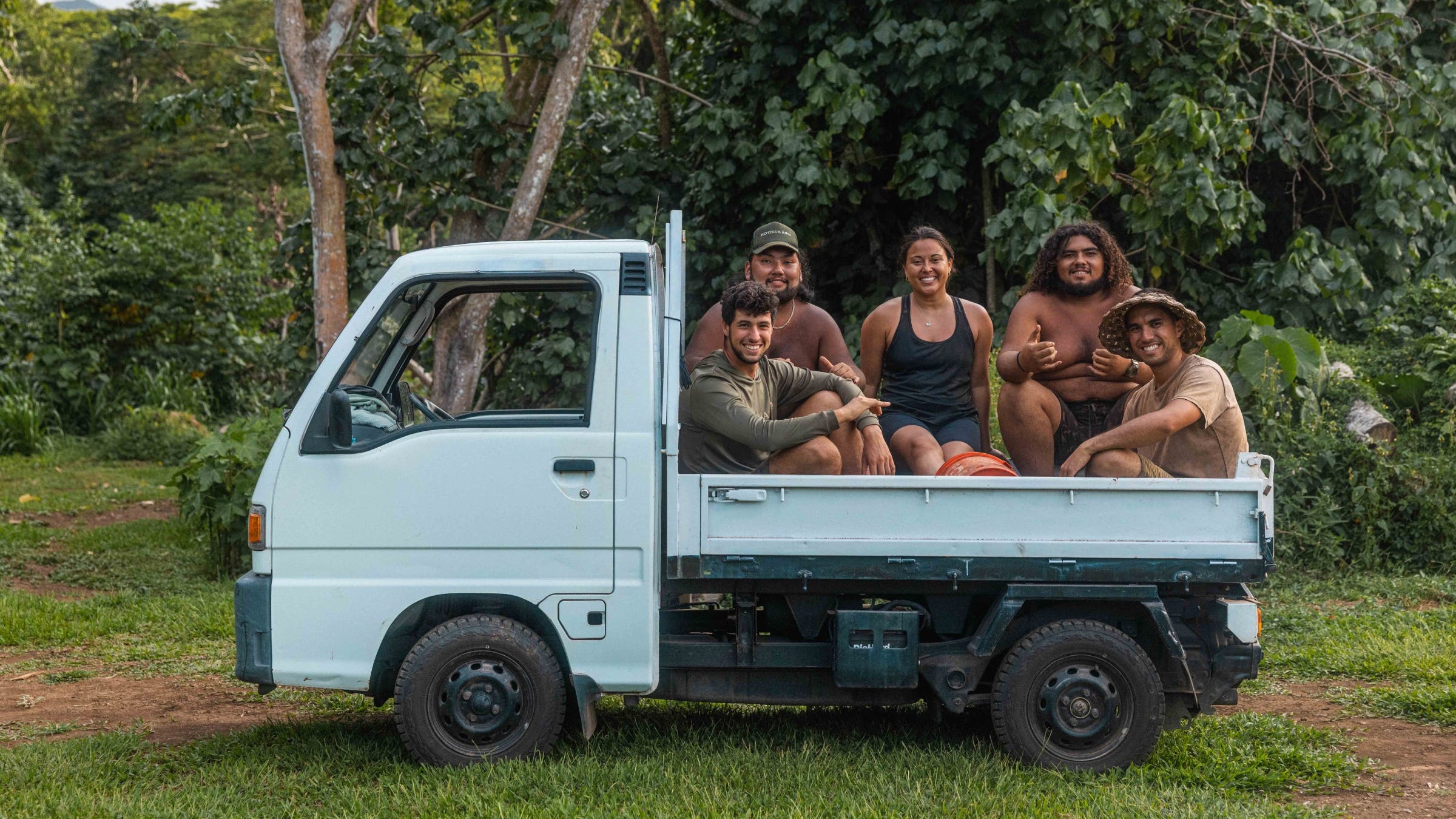 Group of people sitting in a truck bed.