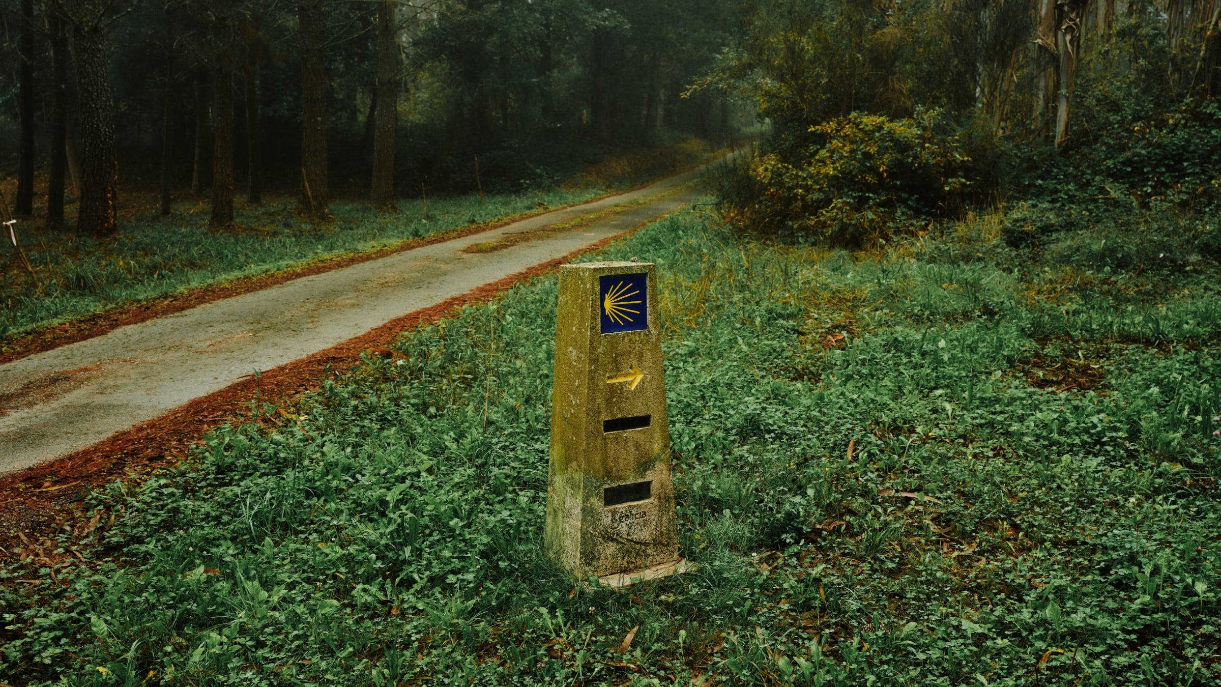 A stone mile marker with a yellow arrow pointing right.
