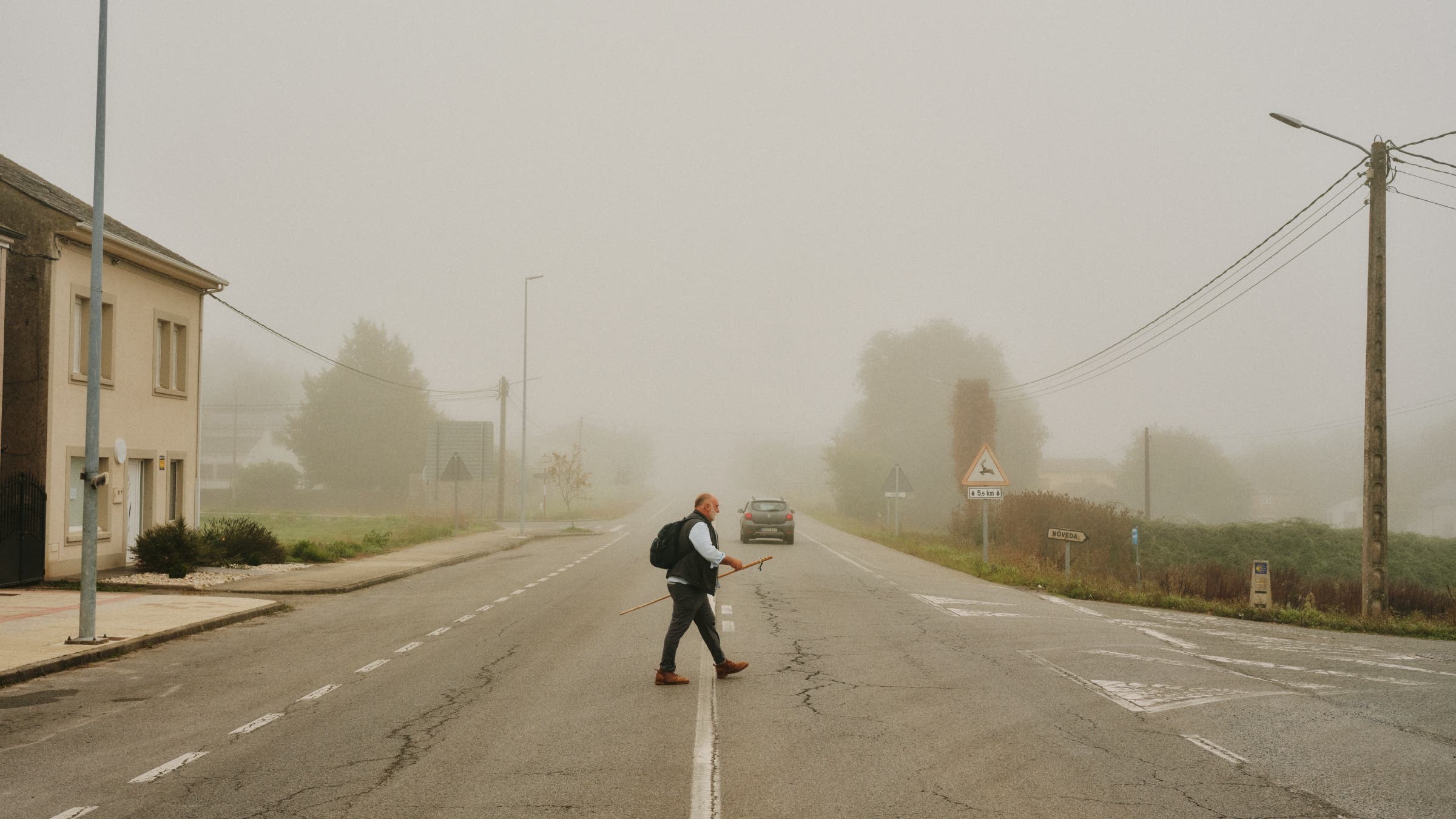 José crosses a road in dense fog.