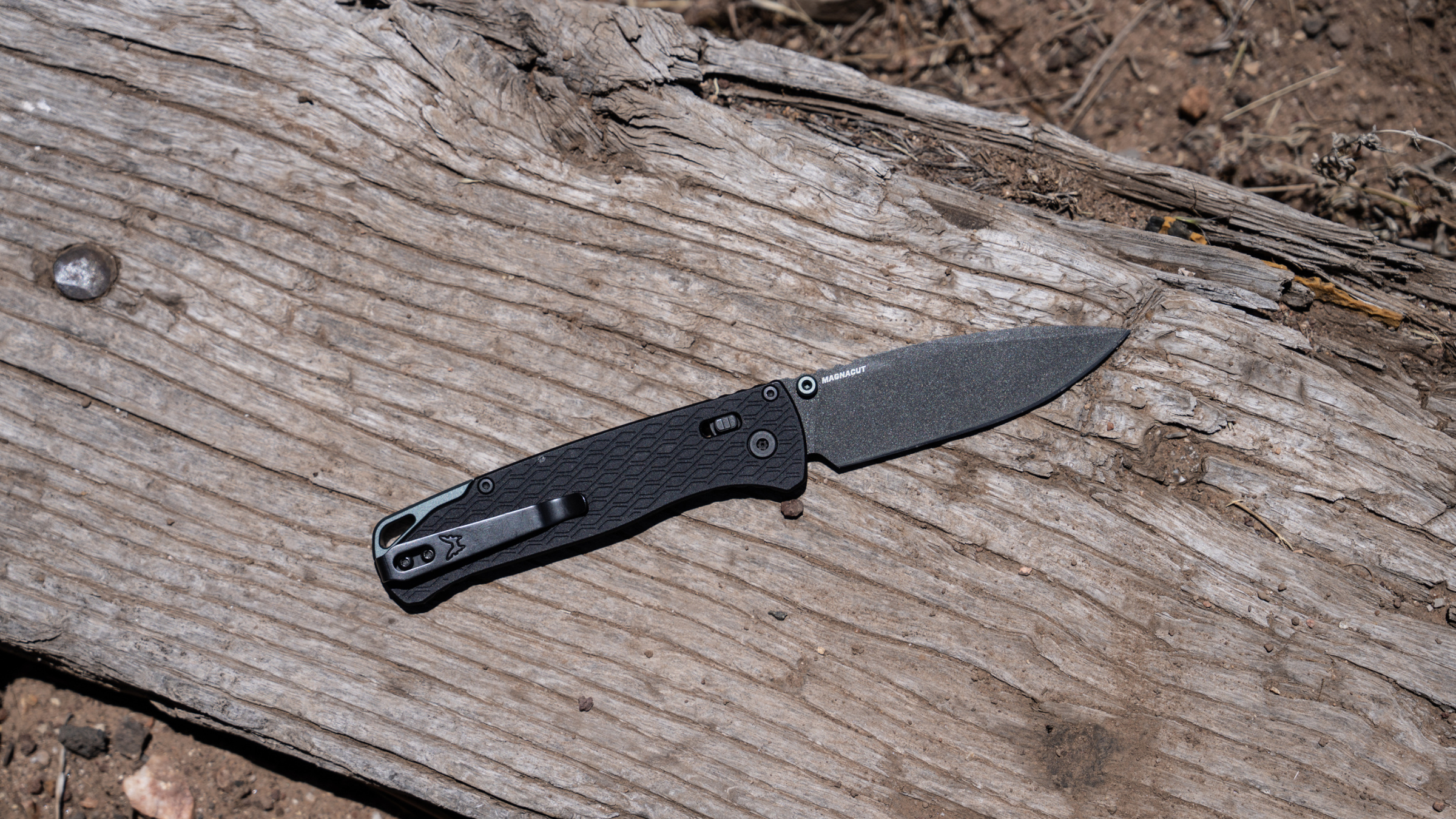 Benchmade knife with black handle lying on a piece of wood outside at 2026 Overland Expo West