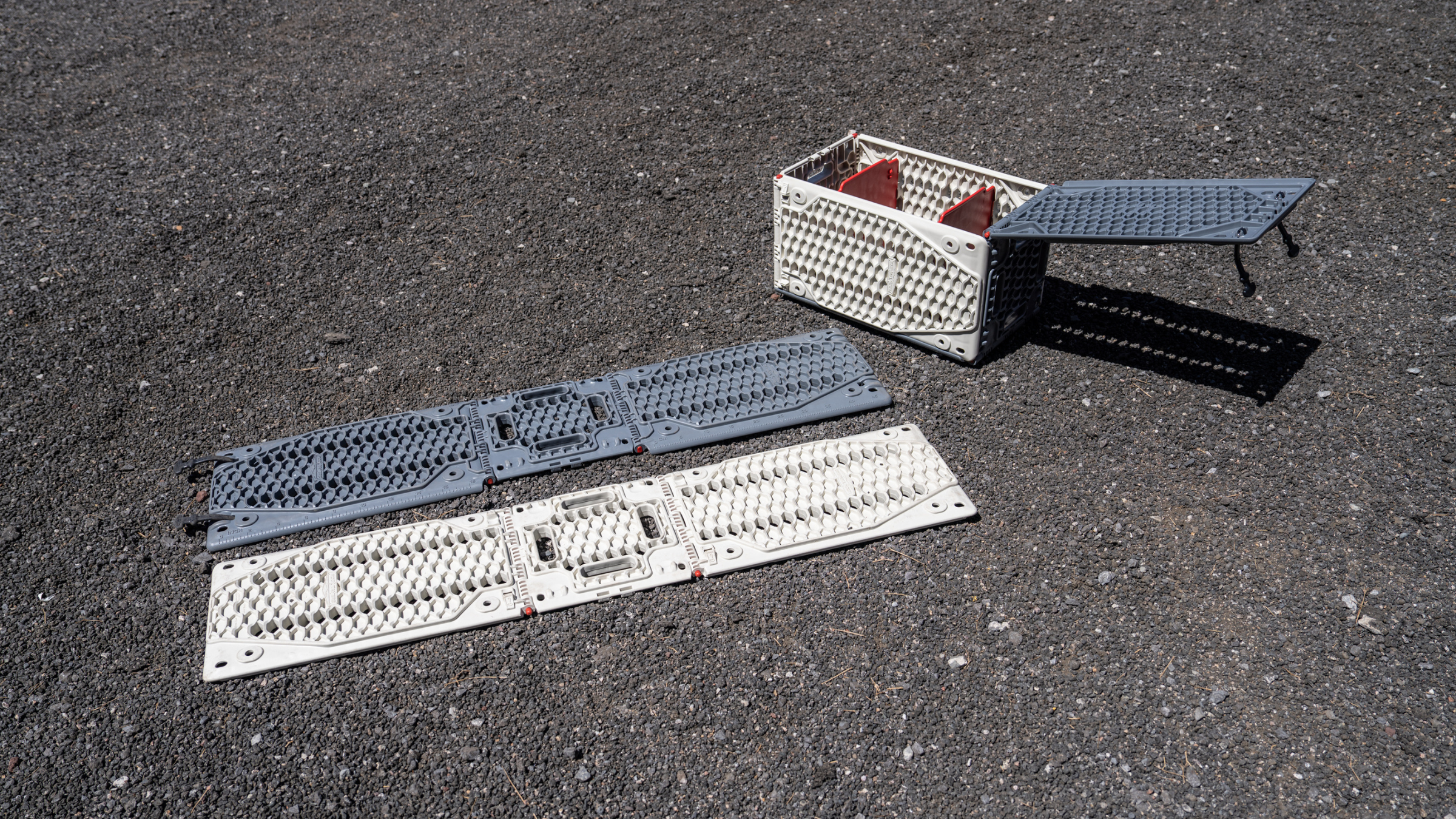 two traction boards next to a crate on asphalt outside at Overland Expo West