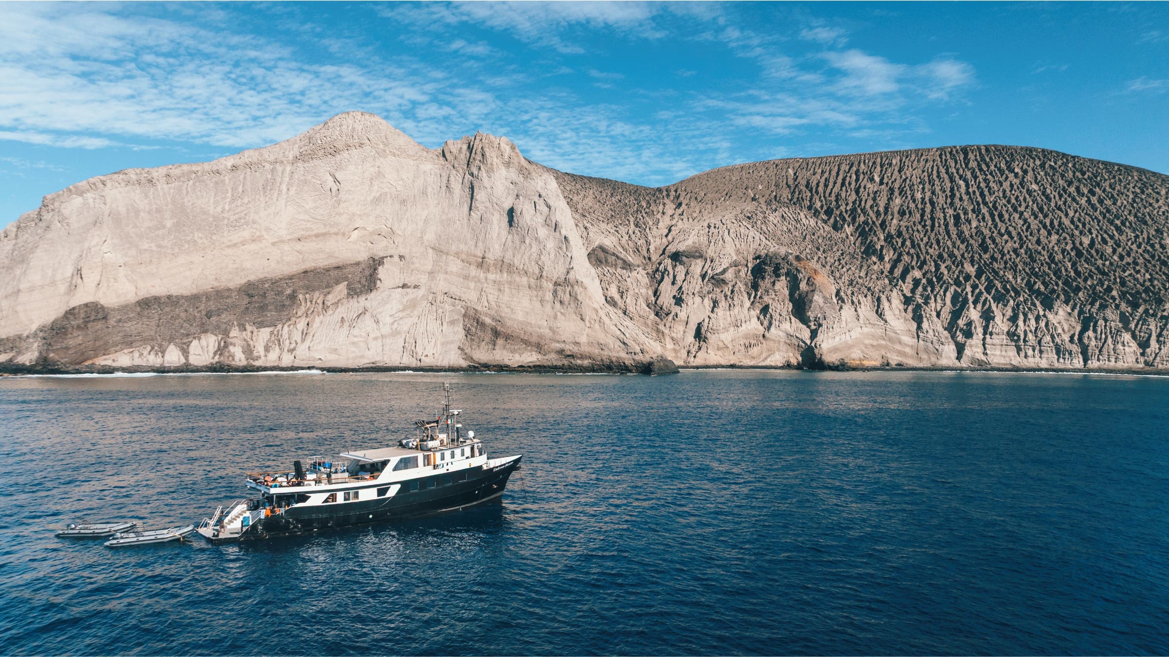 A boat near a rocky island cliff face.