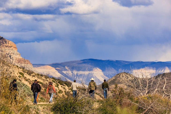 Members of the Colorado Range Rider program walk along a road as they move locations during a track and sign certification class