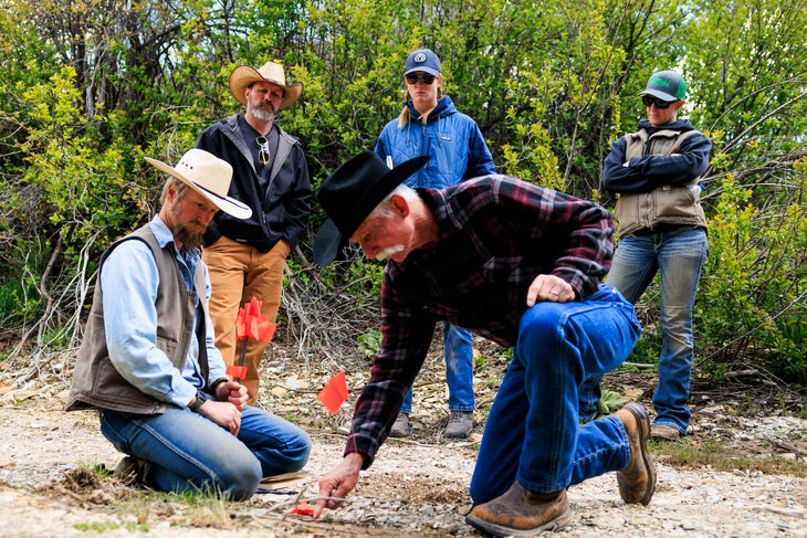 Southwest Non-Lethal Mitigation Specialist for the Colorado Department of Agriculture Jesse Lasater, back left, and Defenders of Wildlife Range Rider Christina Vander Berg, back right, watch as CyberTracker instructors discuss a coyote print.
