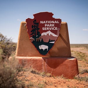 PETRIFIED FOREST, AZ - APRIL 17: The National Park Service (NPS) logo at the entrance to the Petrified Forest National Park, the only National Park that contains a segment of the historic Route 66, on April 17, 2026 in Petrified Forest, Arizona. A hundred years later, Route 66 remains one of America’s most iconic road trips. Its neon signs, roadside stops, and wide-open stretches continue to define the “Mother Road” as visitors enjoy the experience