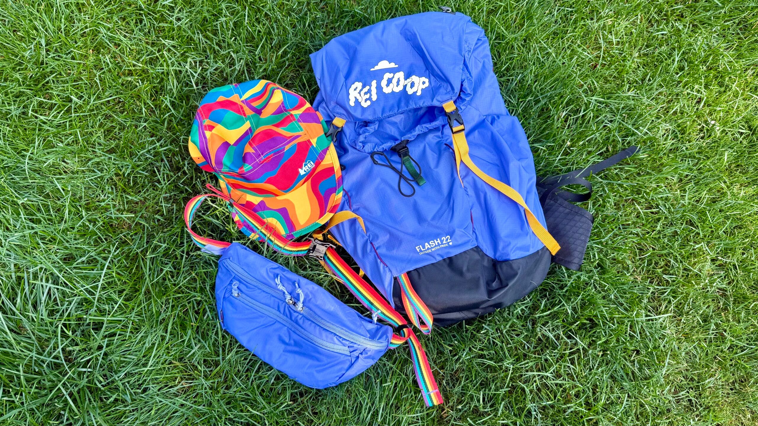 REI Co-op Outside with Pride collection Flash 22 pack, hip pack, and rainbow running hat for Pride Month.