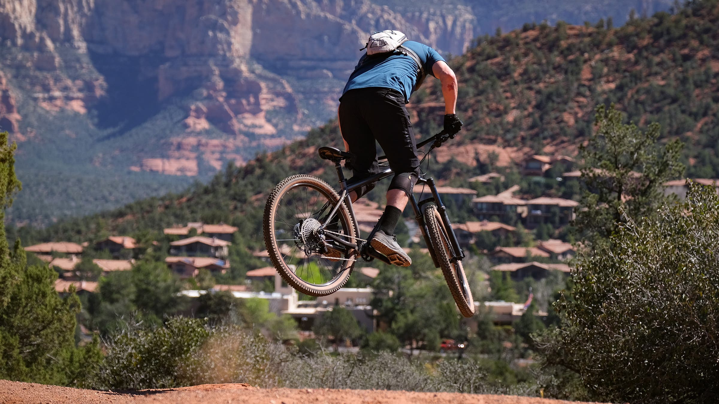 Mountain biker hitting a jump on red rock singletrack in Sedona, Arizona