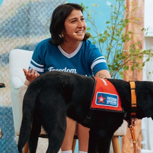 karen perez of freedom service dogs on stage with a black lab, Mango