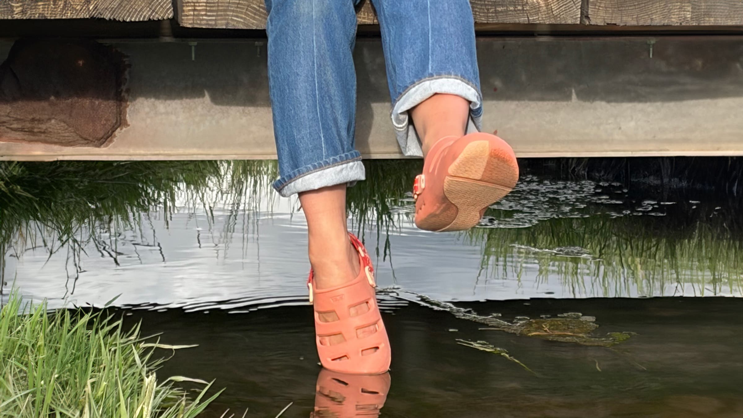 Tester sitting on the edge of a dock wearing Teva ApreAqua Closed-Toe Water Sandal water shoes