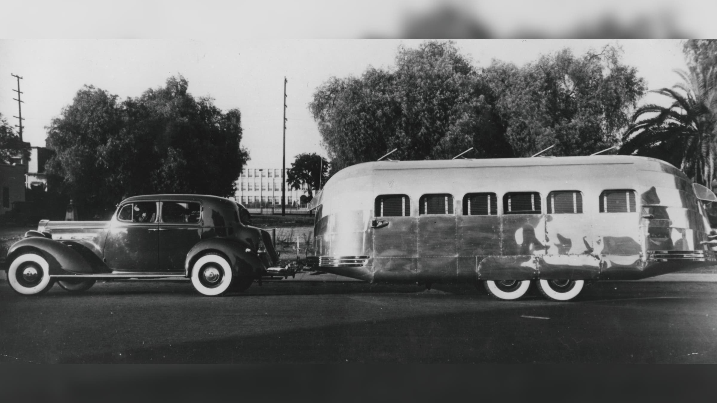 Old photograph of a car towing an Airstream.