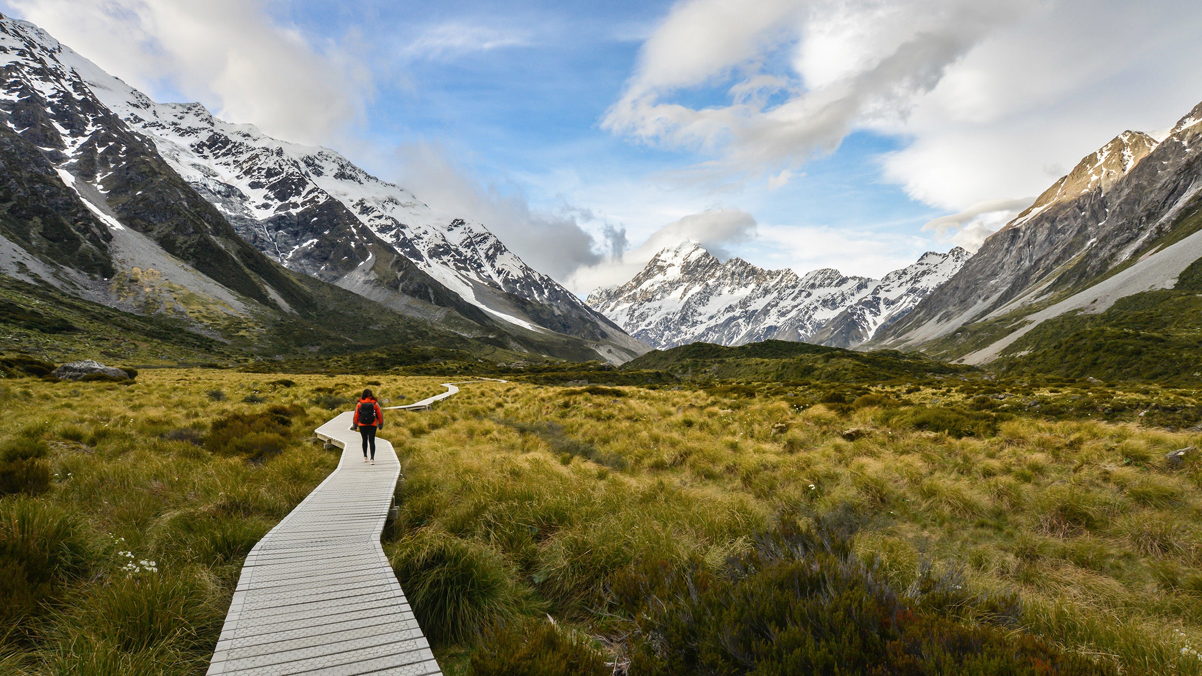 Woman backpacker walking on the wooden way to Mt Cook in New Zealand