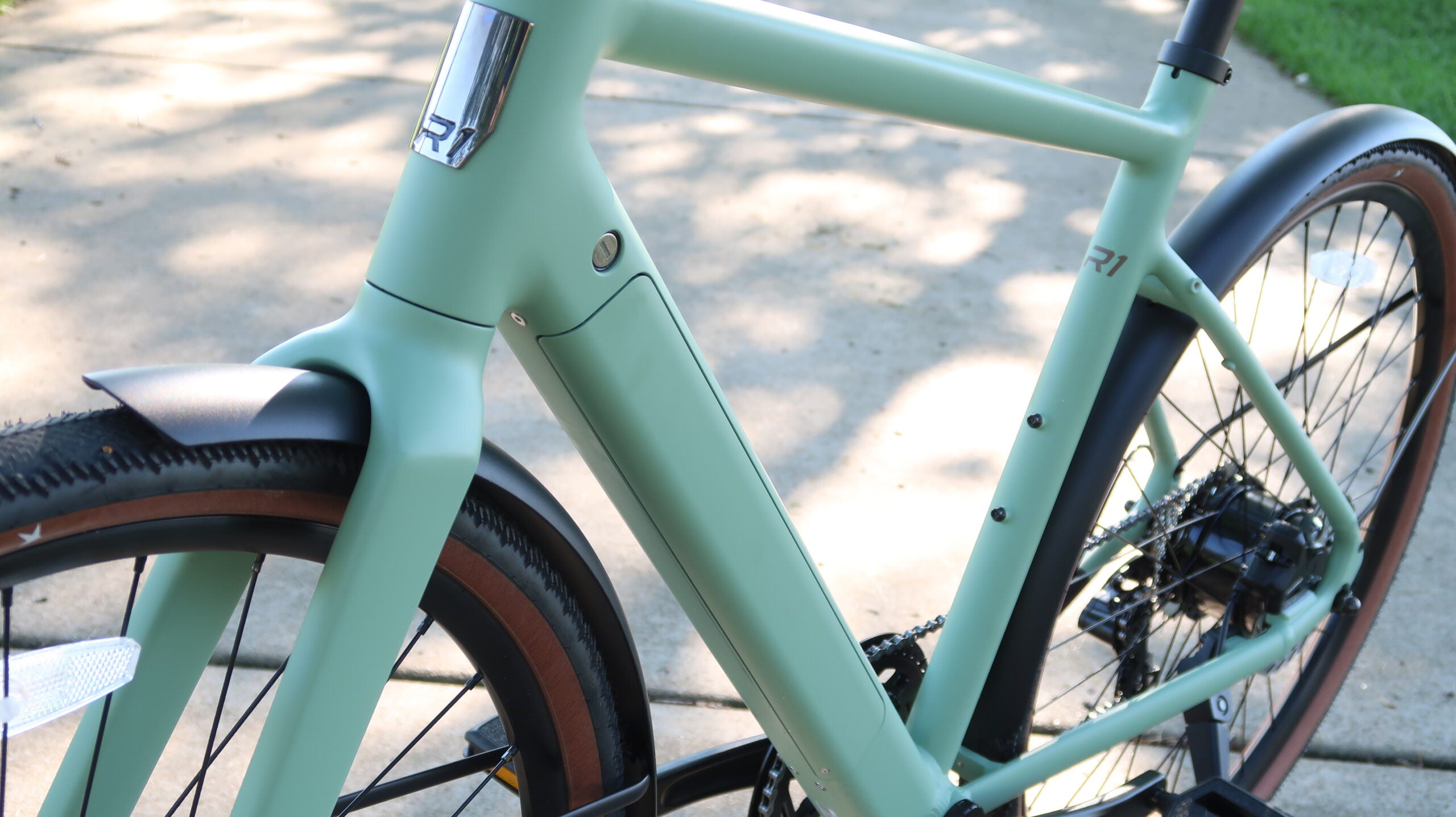 Close-up of the Ride1Up Roadster V3's sage green frame with integrated downtube battery.