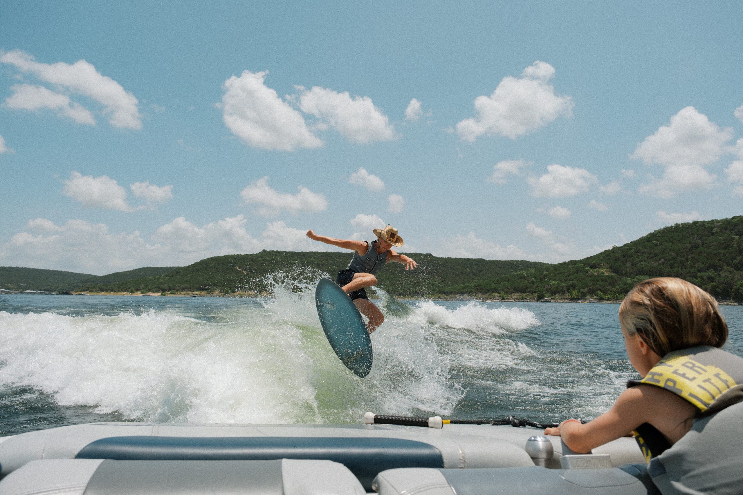 Man wearing a cowboy hat wake surfs on Lake uatin