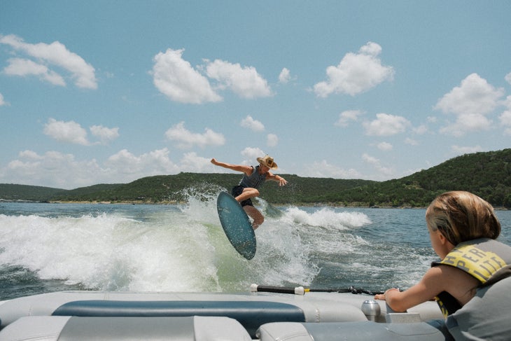 Man wearing a cowboy hat wake surfs on Lake uatin