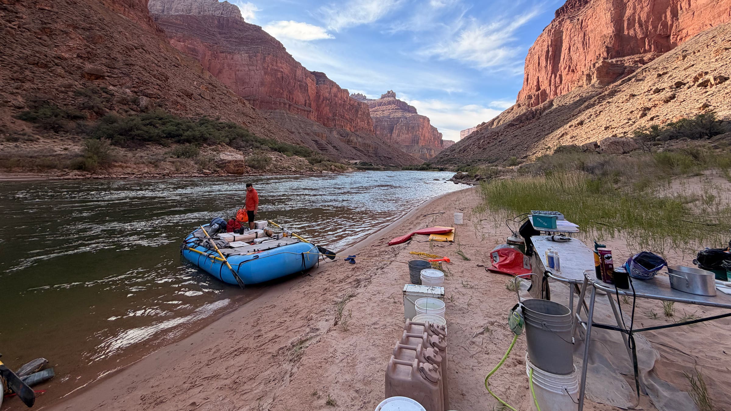 A river raft on the edge of the riverbank on a Grand Canyon floating trip with gear spread out all around