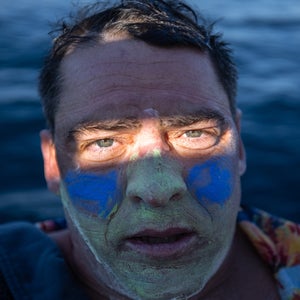 Rob Lea's face is photographed with blue and green zinc as he swims in the ocean