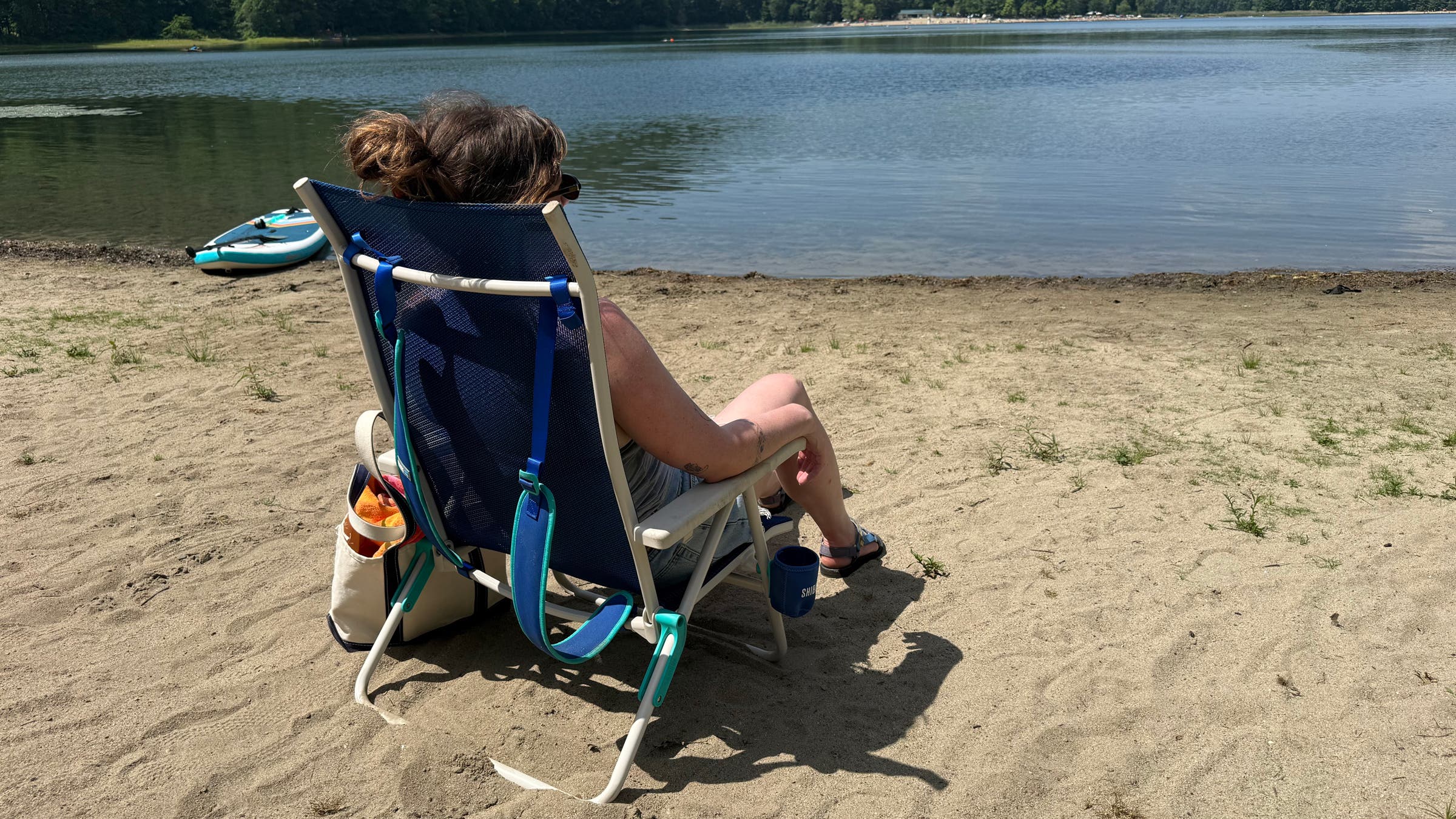 Shibumi folding beach chair at the lake with tester sitting on the recliner