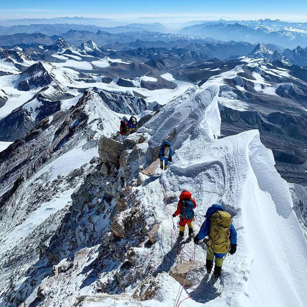 Rob Lea photographed with other mountaineers walking along the spine of a mountin in the Mount Everest region