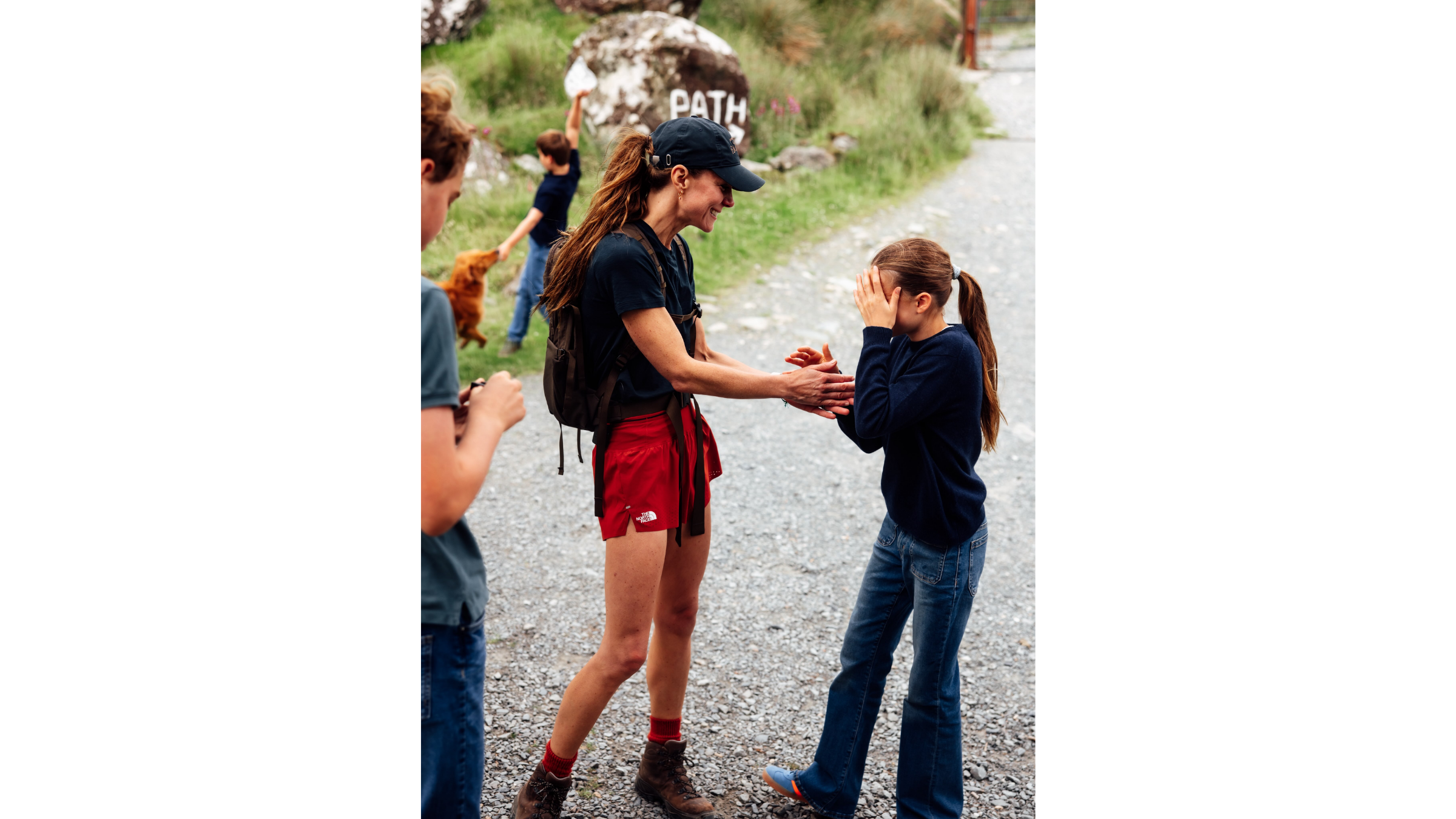 Kate Middleton, Princess of Wales, celebrates completing the Three Peaks challenge with daughter Princess Charlotte, wearing a Fjallraven hat, navy blue hiking top, red The North Face running shorts, and hiking boots