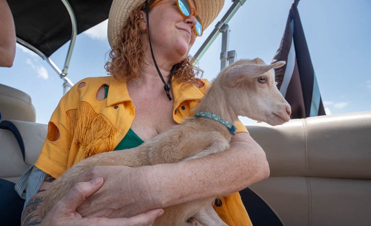 woman holds a small goat on a boat at the boatsetter rodeo
