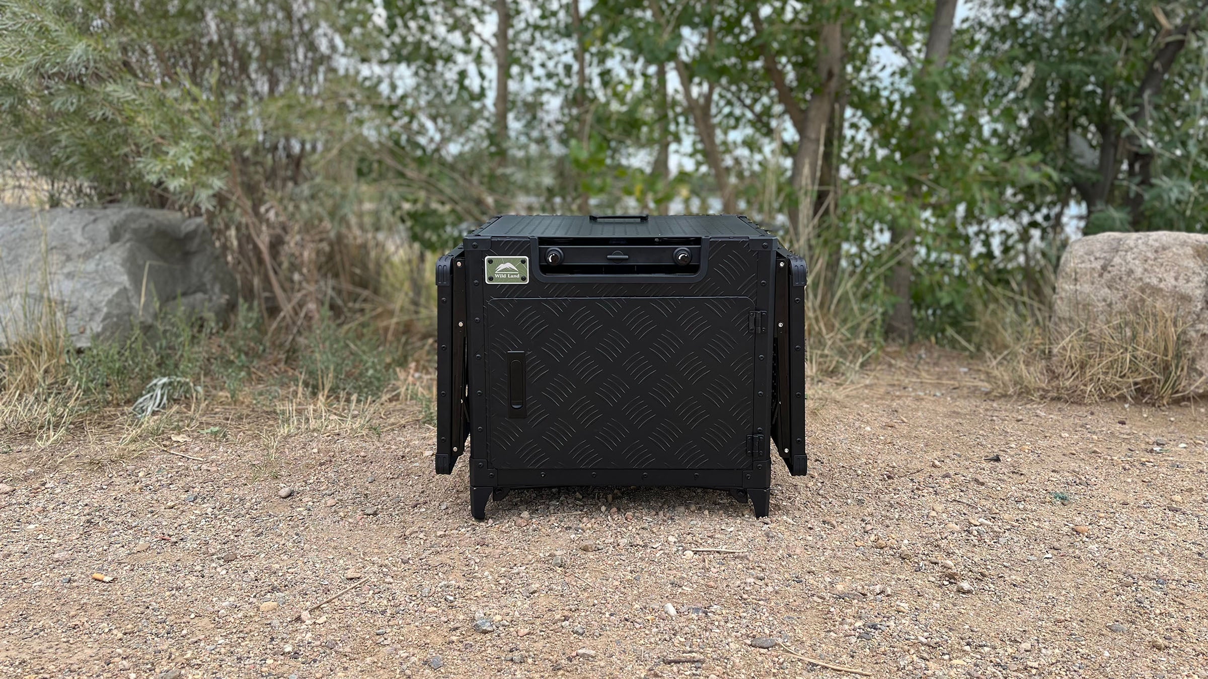 The Cinch Kitchen Cruiser folded down into its packed, box-shaped form in a gravel lot.