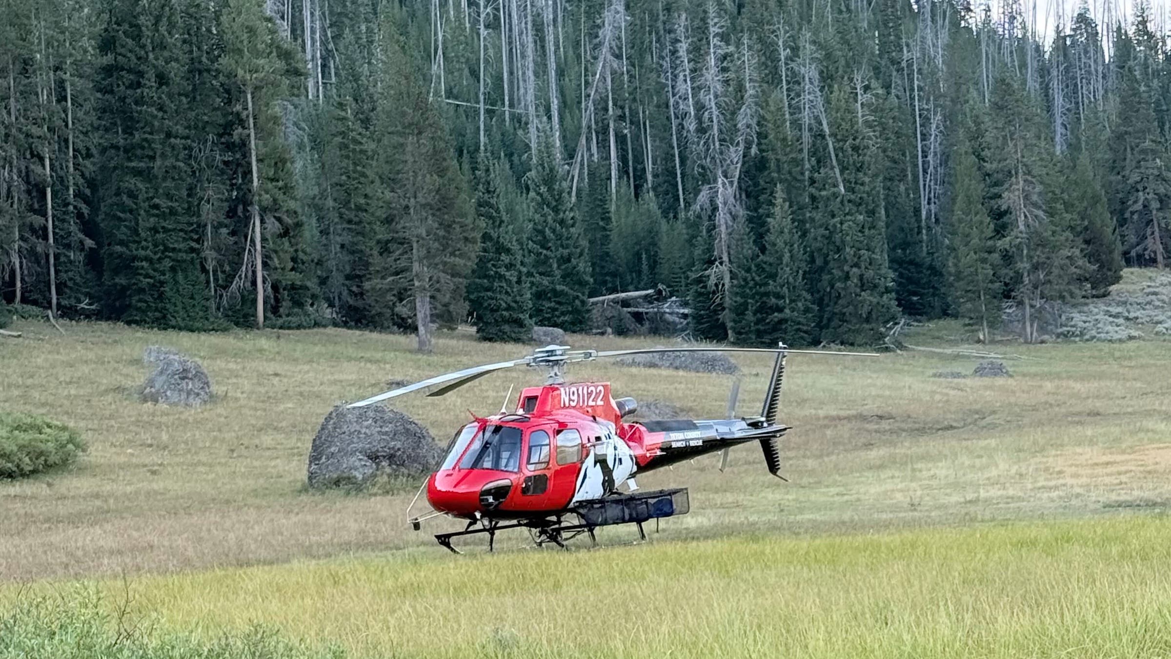 red helicopter shown in a field 