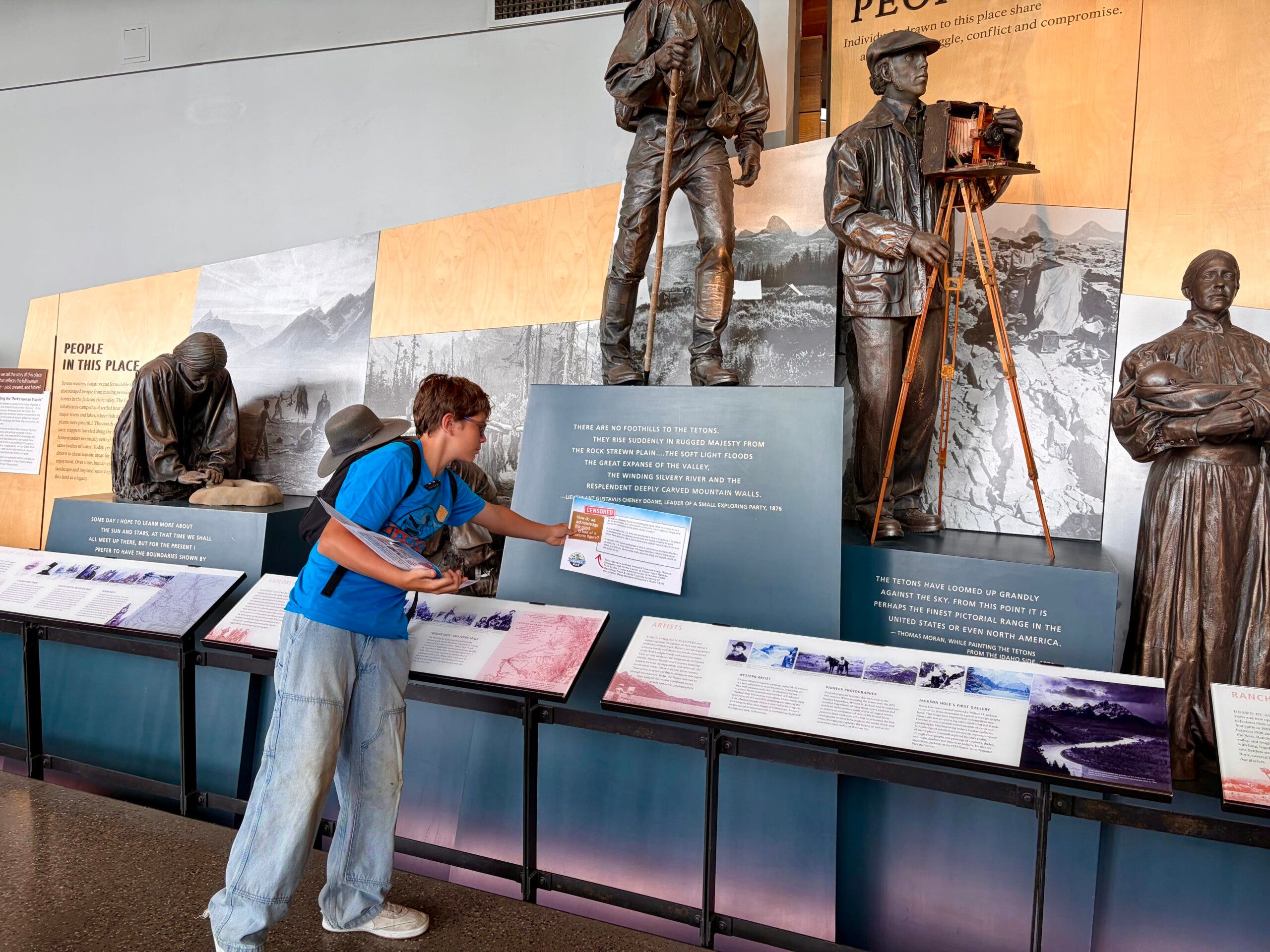 Melissa's son Jacob shown points out where a sign used to be in pointing out where the missing sign went in the Craig Thomas Visitor and Discovery Center in Grand Teton National Park