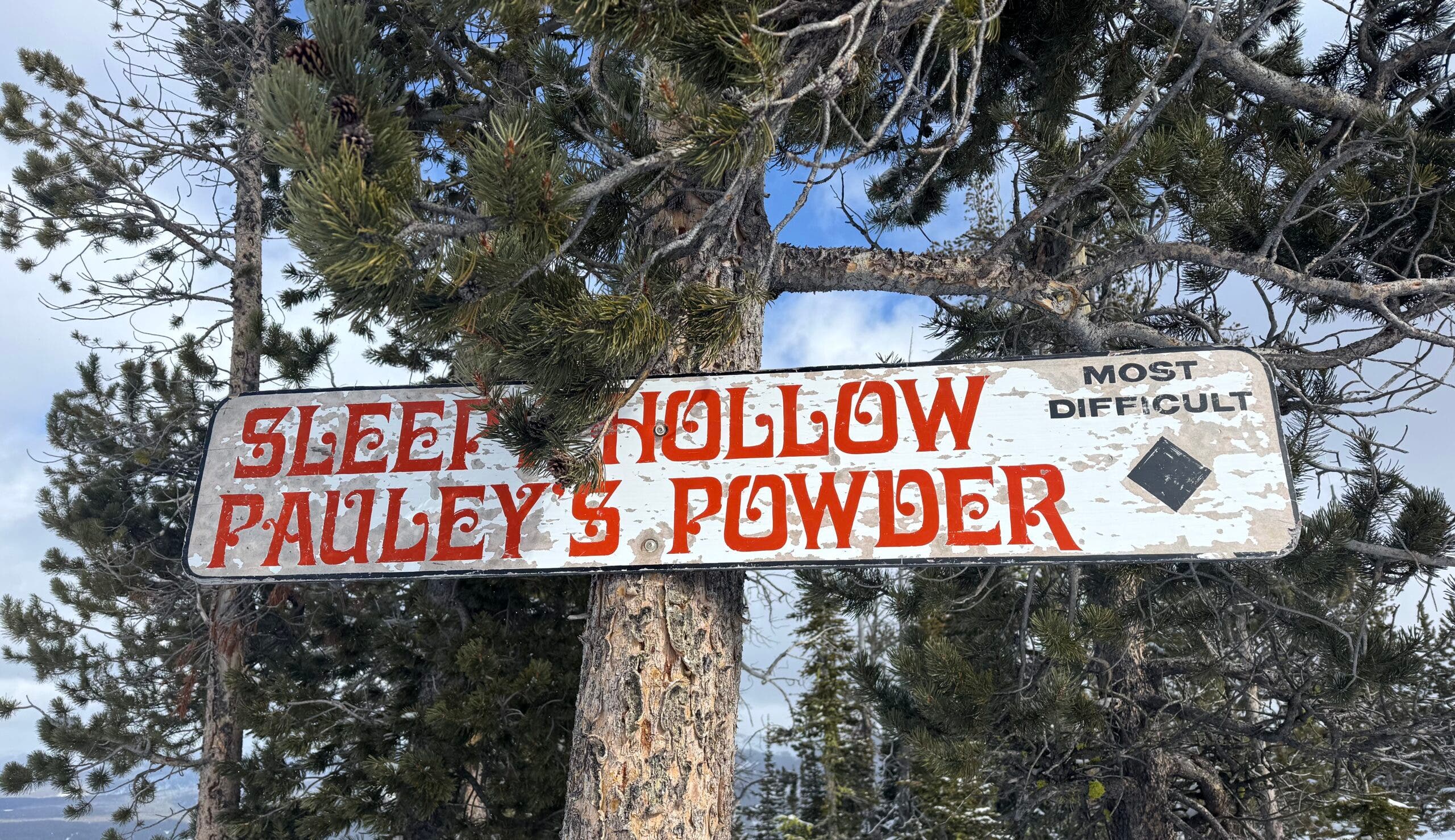 a sign shows the names of two ski runs, sleepy hollow and pauley's powder