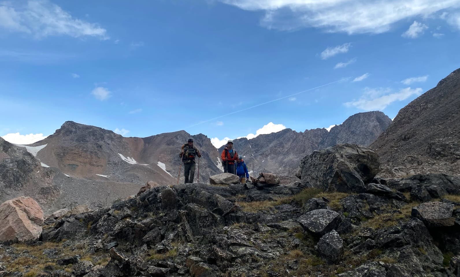 search and rescue crews on a rocky slope with mountains in the background