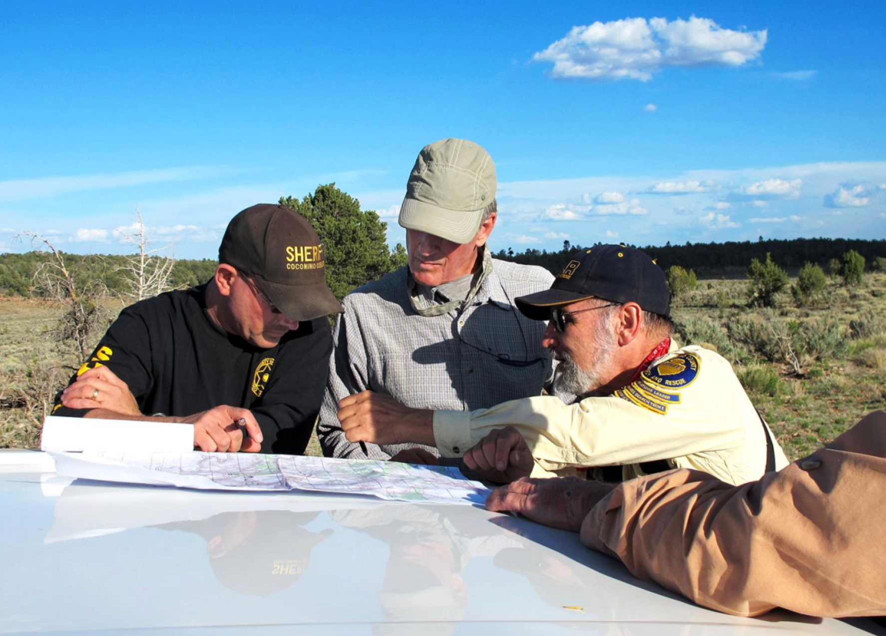 Aaron Dick, Scott Thybony and Art Pundt review maps while searching for Bill Ott in 2012