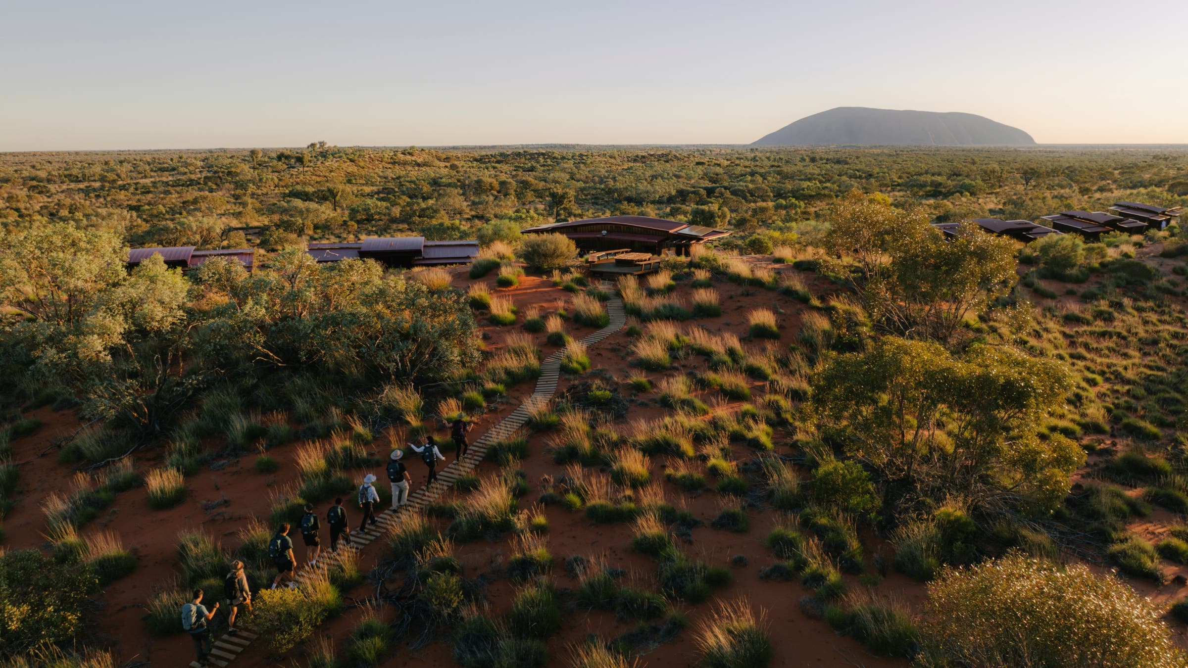 Aerial shot of hikers walking in a line to a camp outside of Uluru.