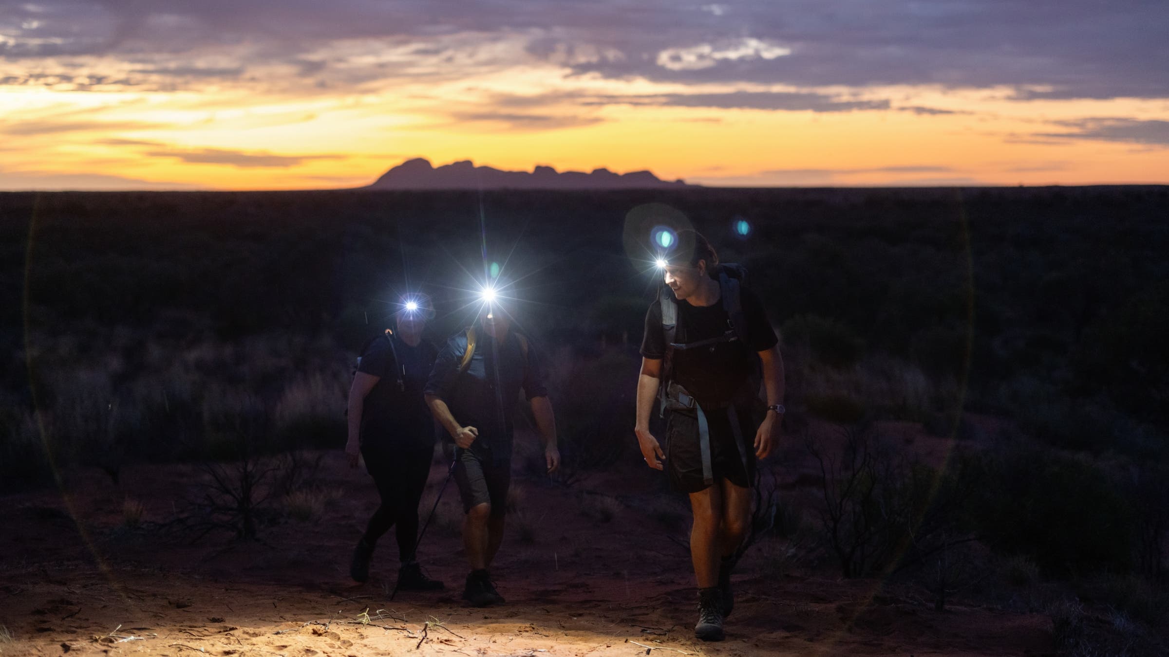 Hikers walking in dim light with headlamps.
