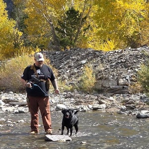 adam borkhus and his black labrador retreiver diesel photographed standing in a river