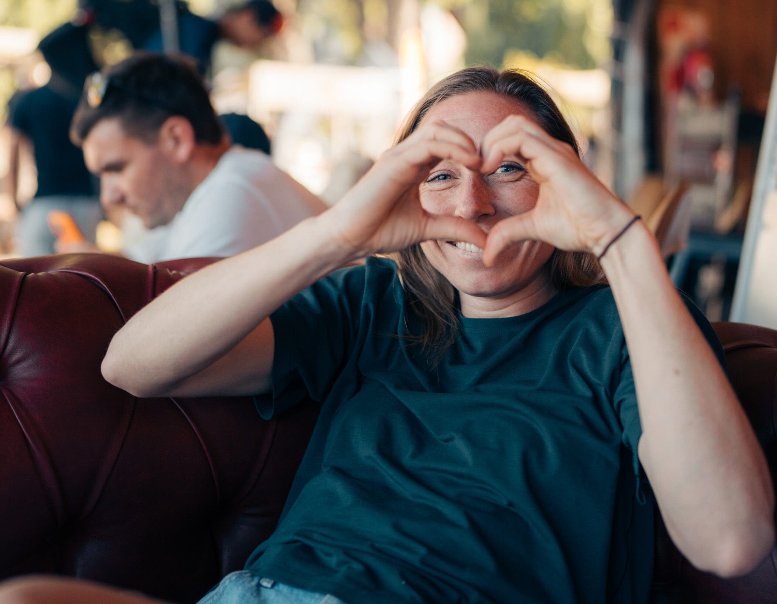 kalie shown sitting in a brown chair making a heart with her hands