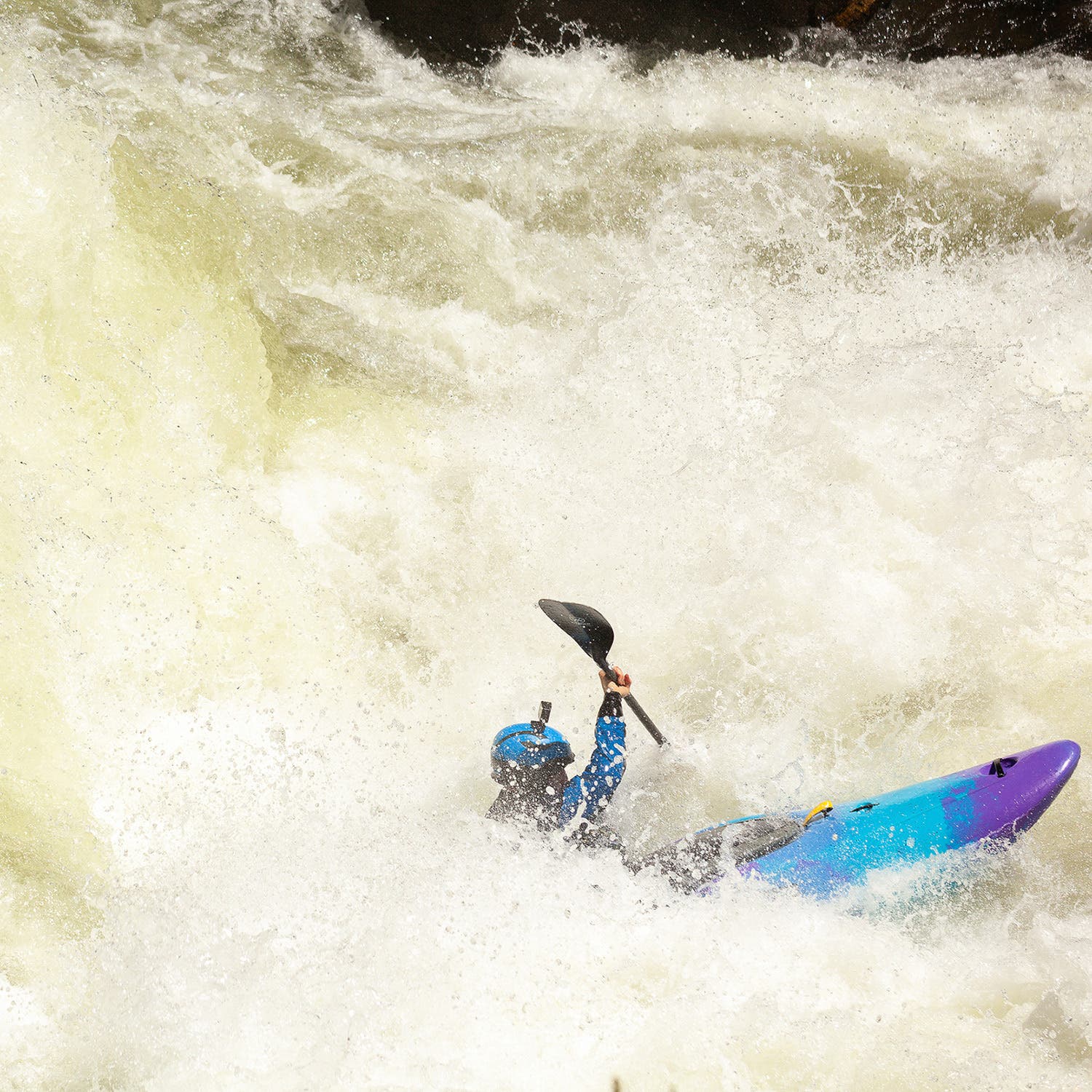 a paddler a blue and purple kayak is shown buried in whitewater