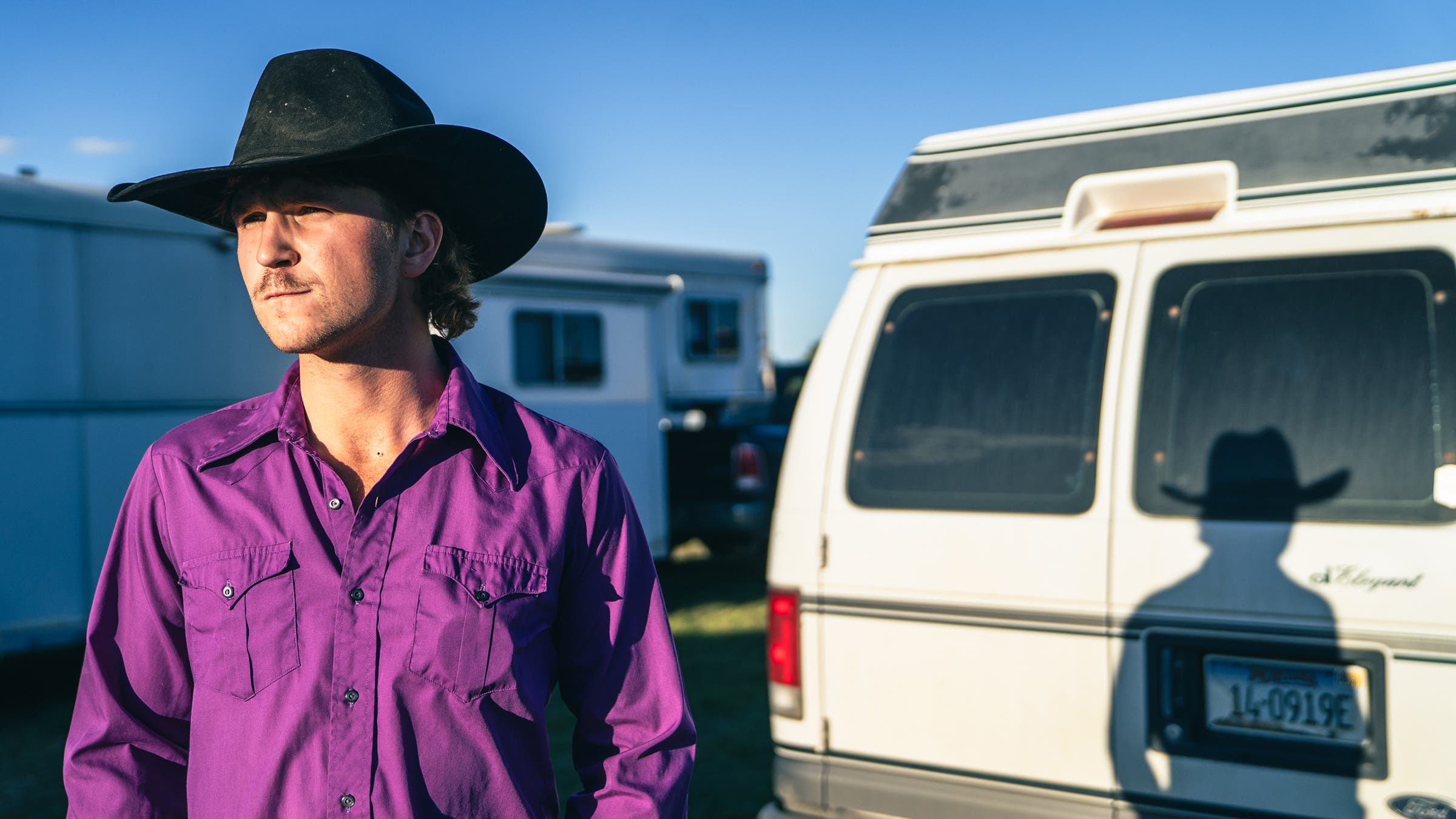 cowboy in black hat with setting sun throwing his shadow