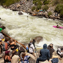 a kayaker in a pink boat is shown paddling down jacob's ladder on the north fork of the payette near banks, idaho, with a crowd nearby