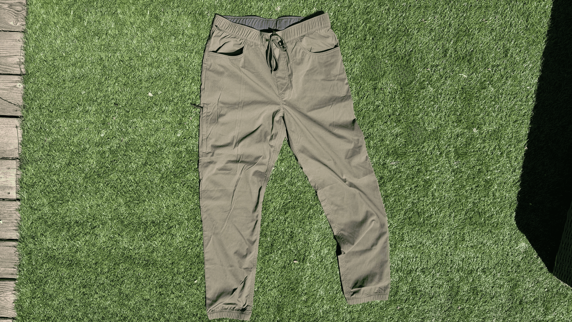 pair of men's olive green Patagonia joggers lying flat on green turf outside
