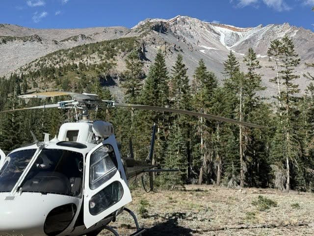 a helicopter shown in the foreground with mount shasta in the background