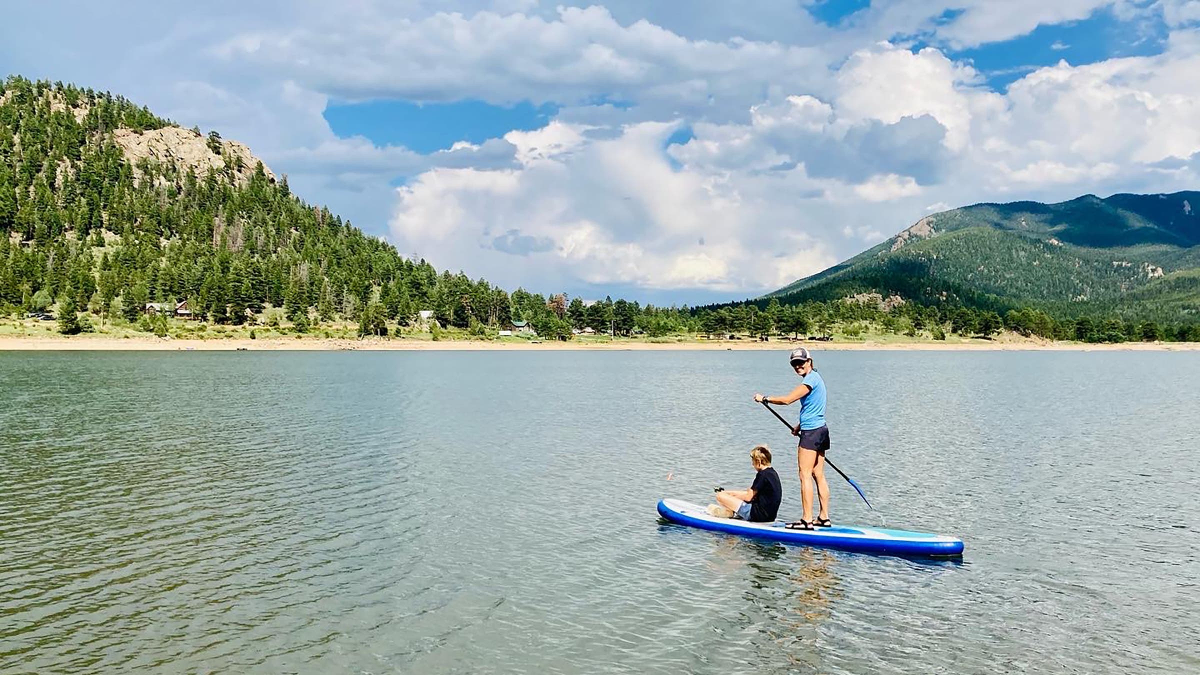 woman and boy on a stand-up paddleboard on a mountain lake