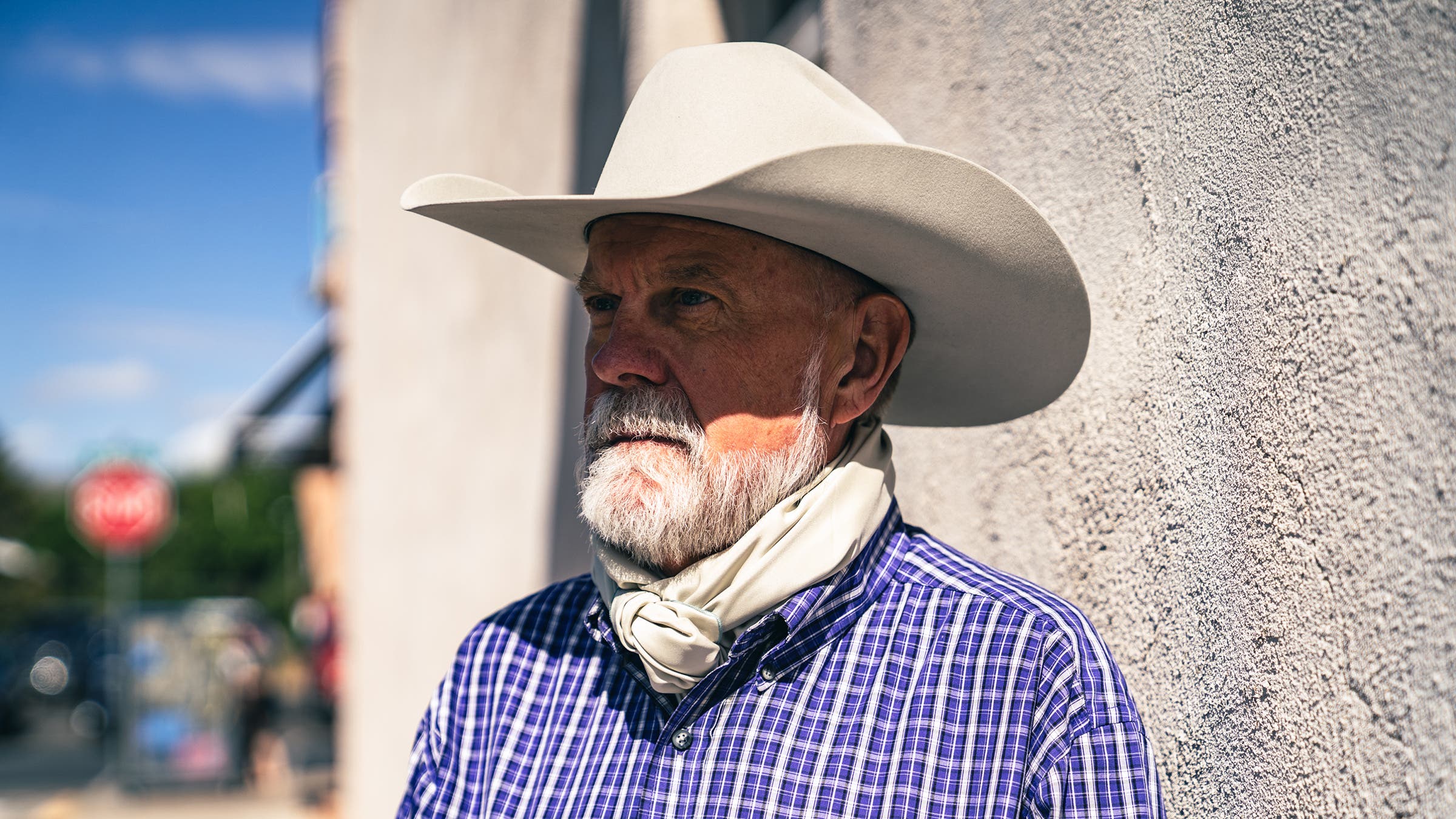 cowboy in purple shirt and white hat wearing wild-rag neck wrap