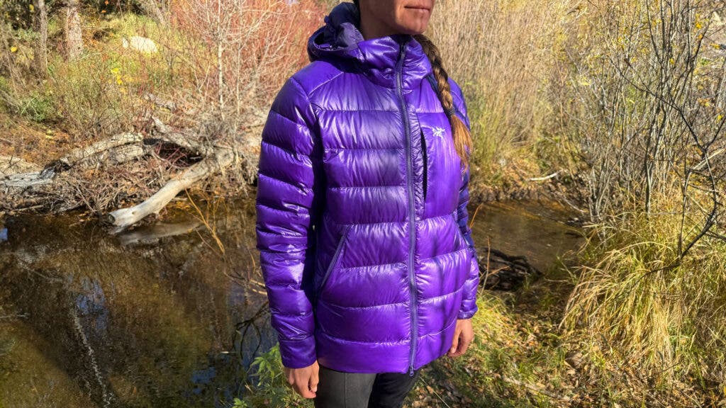 Hiking tester wearing purple Arc’teryx Cerium SV Hoody in the forest