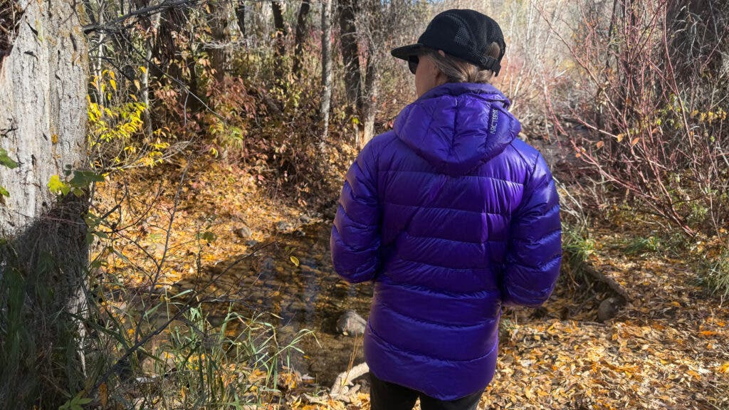 Hiking tester wearing purple Arc’teryx Cerium SV Hoody in the forest
