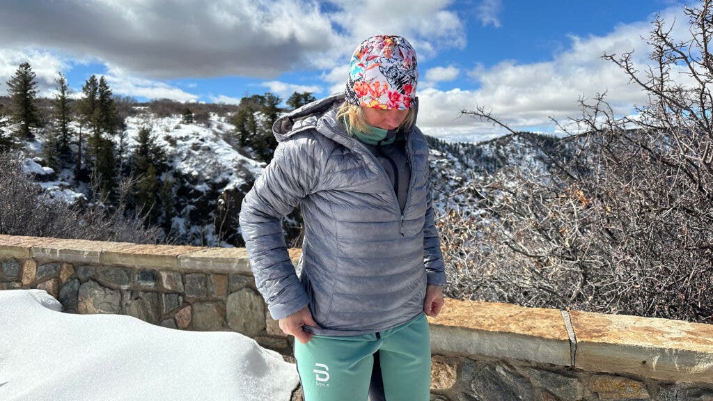 Tester wearing grey Black Diamond Deploy Down .5 Pullover Hoody while cross country skiing under bluebird skies