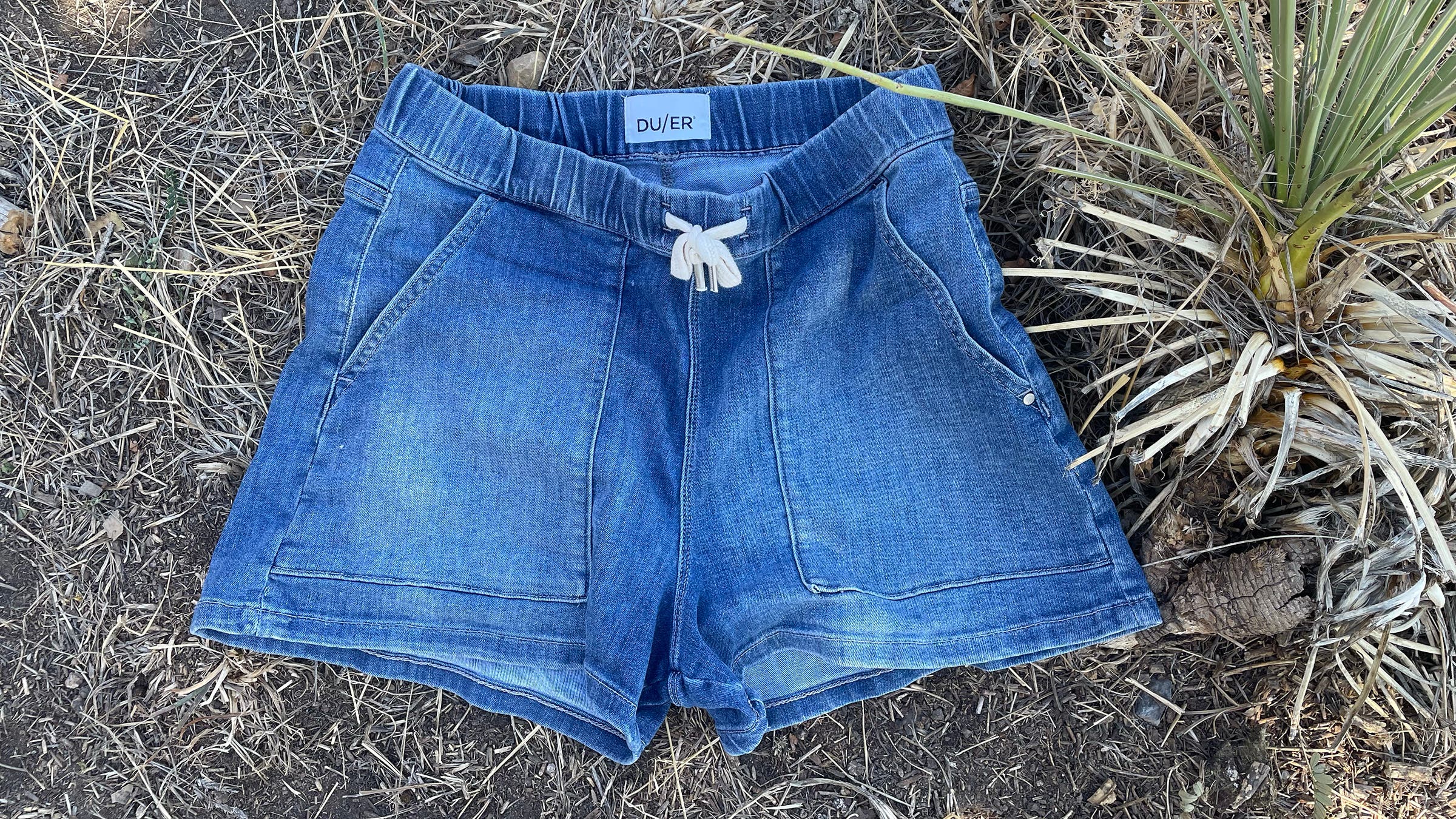 Duer performance denim shorts on weedy background