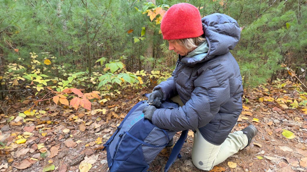 Tester packing backpack on the trail wearing grey Patagonia Durable Down puffy jacket