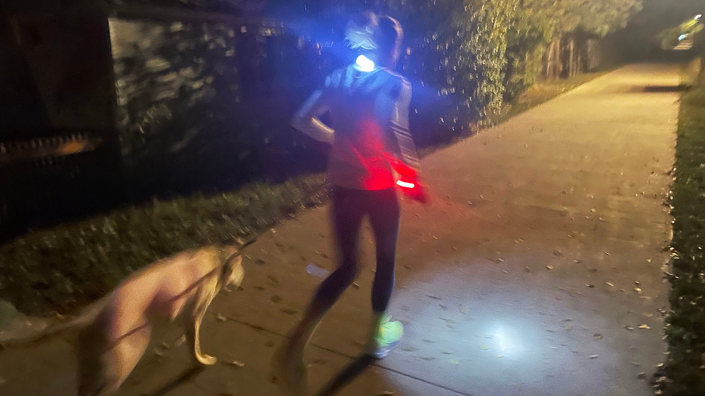 Runner jogging at night with reflective gear and lighting in the darkness.