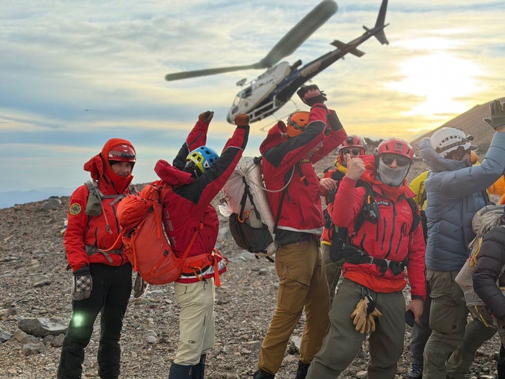 Search and rescue team members are shown as a California Highway Patrol helicopter takes off with an injured climber on board