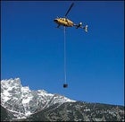 A park service chopper hoists a honey bucket out of the Tetons.