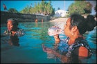 Two Tuvaluans munch raw fish heads as the sun goes down on Funafti's lagoon.